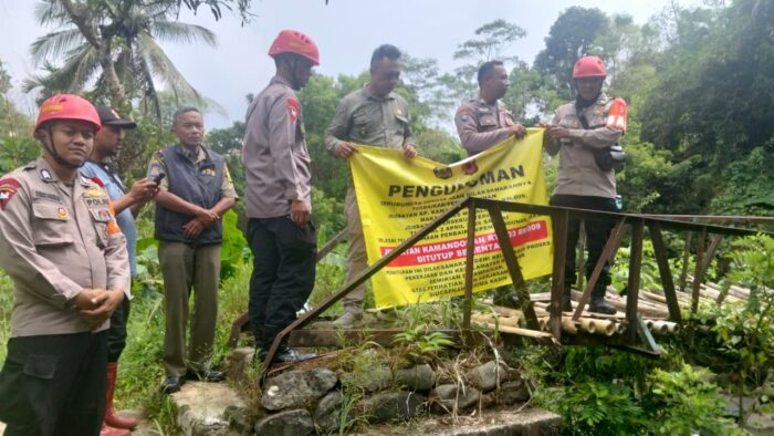 Anggota Polres Sukabumi dan petugas Disperkim Kabupaten Sukabumi memasang spanduk pemberitahuan penutupan sementara jembatan di Kamandoran, Kecamatan Cibadak karena akan dibangun ulang, Sabtu (04/04/2026).