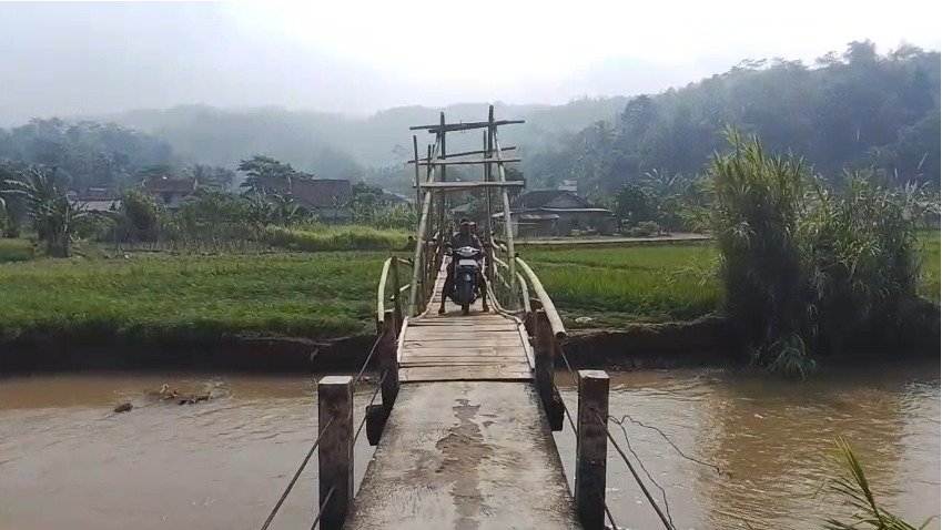 Seorang pemotor melintasi Jembatan Caringin, penghubung Desa Caringin, Kecamatan Gegerbitung dengan Desa Bencoy, Kecamatan Cirenghas, Kabupaten Sukabumi, Jumat (01/05/2026). Kondisi jembatan butuh perbaikan setelah rusak terdampak gempa beberapa tahun lalu. (Foto: Fajar Sidik/Sukabumiku.id)